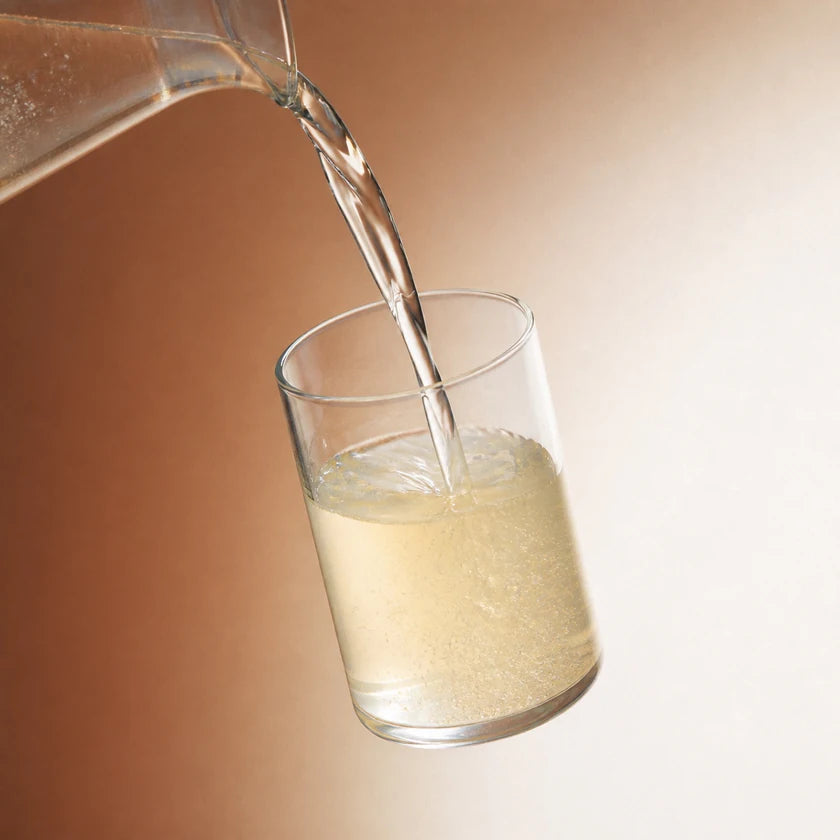 Cold water pouring into a floating glass as Lemon Drop begins to dissolve